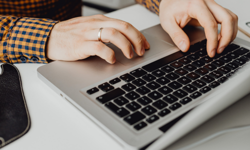 A close up of hands typing on a laptop